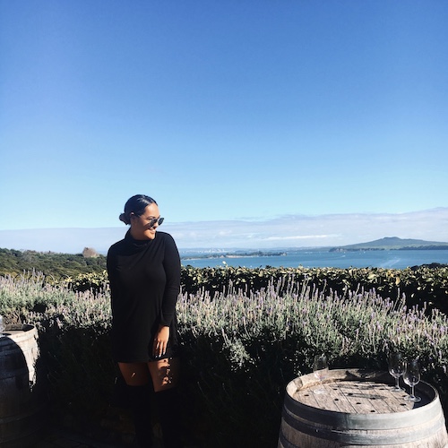 1 girl standing in front of Hills and OCean scenery on Waiheke Island